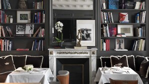 A dining area with two tables set for four, flanked by bookshelves filled with books and framed pictures. - Marquis Faubourg Saint Honoré - Small Luxury hotels of the World (Paris)