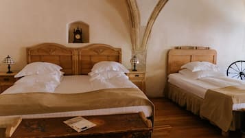 A room with two wooden beds, each with a nightstand and a lamp. There is a small clock on the wall above the left bed.