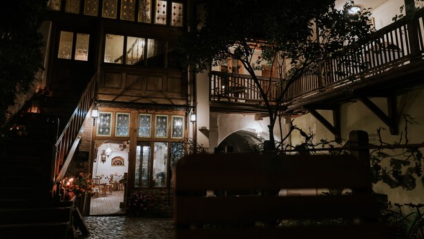 Un edificio tradicional con patio, escalera de madera y un banco.