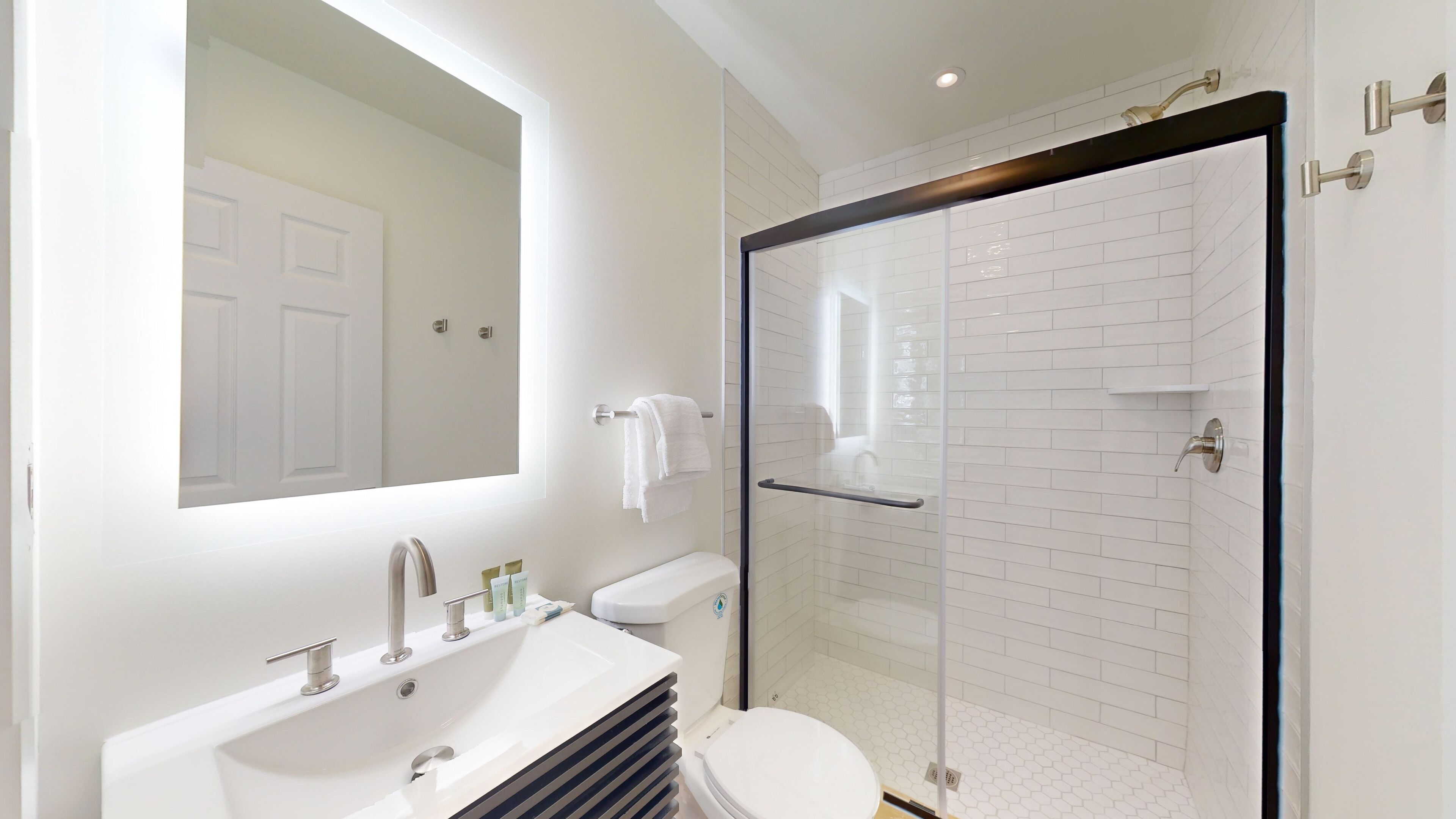 A modern bathroom with a white sink, toilet, and glass shower enclosure.