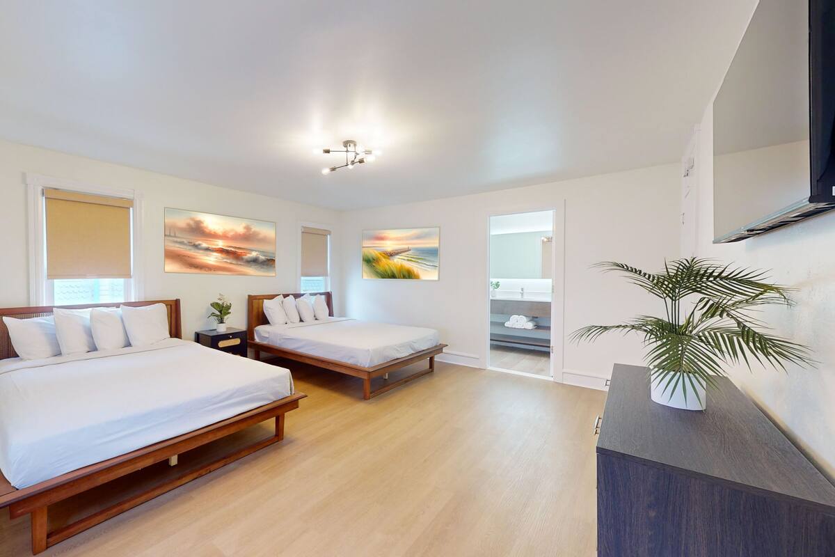 A hotel room with two wooden beds, a large mirror, and artwork on the walls.