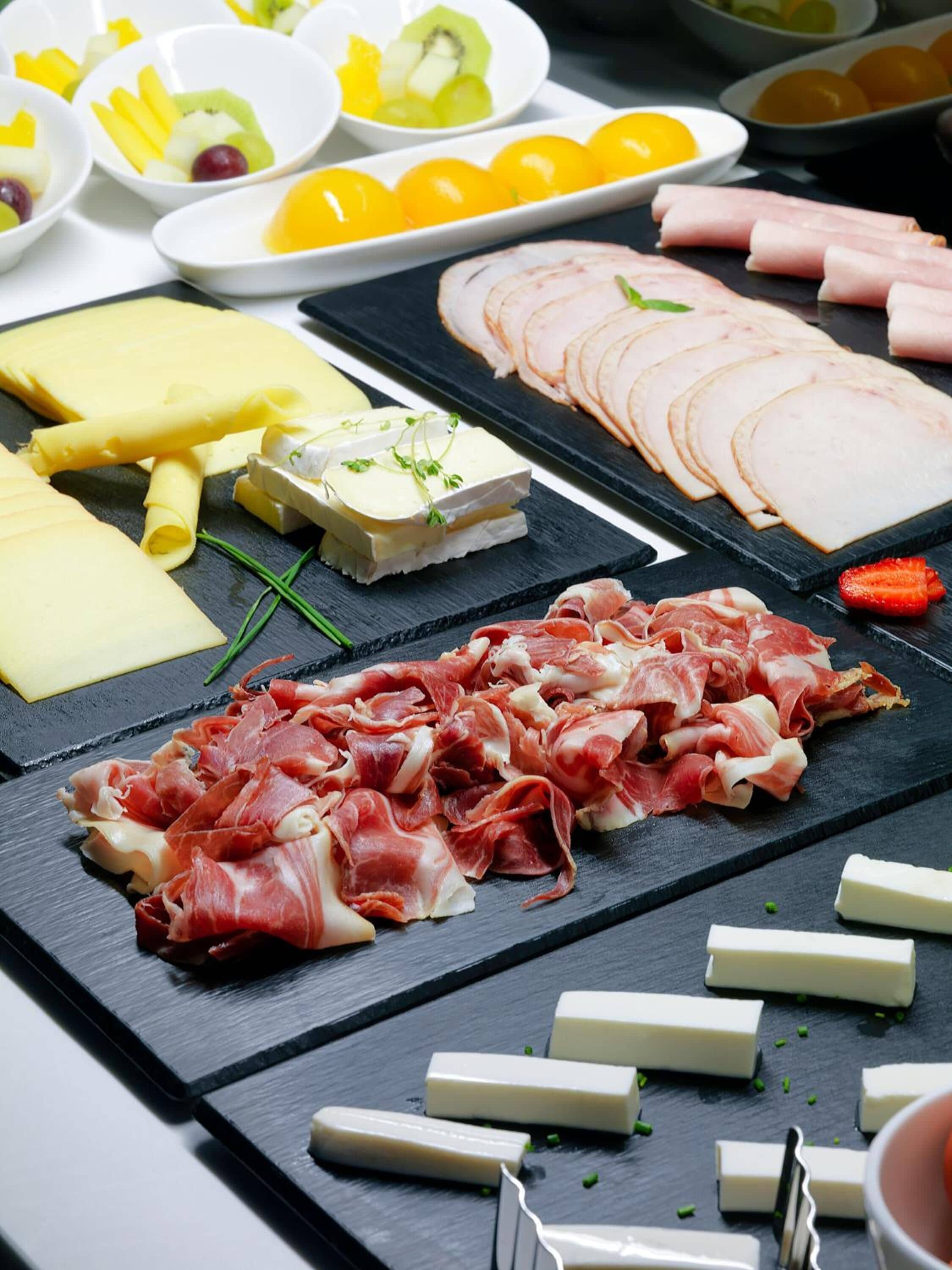 Une planche de charcuterie comprenant divers fromages, des viandes séchées et des fruits.
