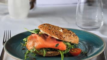 Un sándwich en un plato, con un tenedor y un cuchillo a un lado.