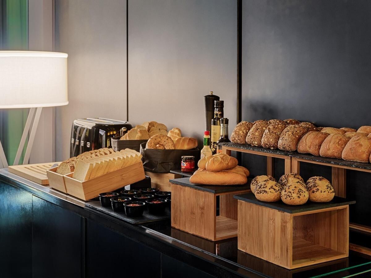 Eine Bäckertheke mit verschiedenen Brotsorten und Backwaren, einer Kaffeemaschine und Beilagen.