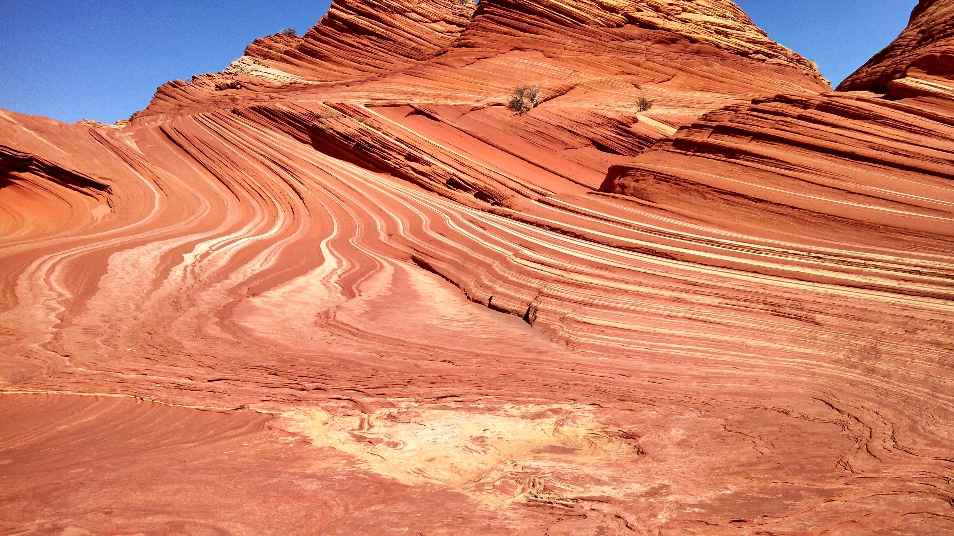 A large, red rock formation with distinct layers and a clear sky.