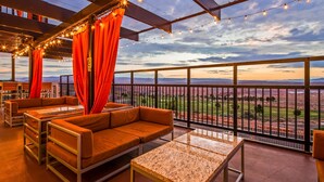 A rooftop terrace with outdoor seating, string lights, and a view of distant mountains. - Best Western View Of Lake Powell Hotel (Page)