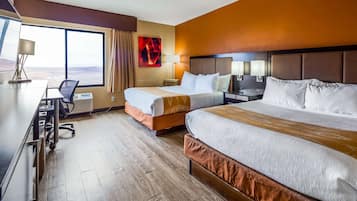 Habitación de hotel con dos camas, un escritorio, una silla, una lámpara y un ventanal grande.