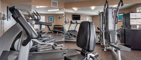 A gym with treadmills, elliptical machines, and weightlifting equipment.