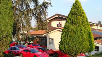 Un hotel con un letrero que dice "Best Western PLUS". Varios autos deportivos rojos están estacionados adelante.