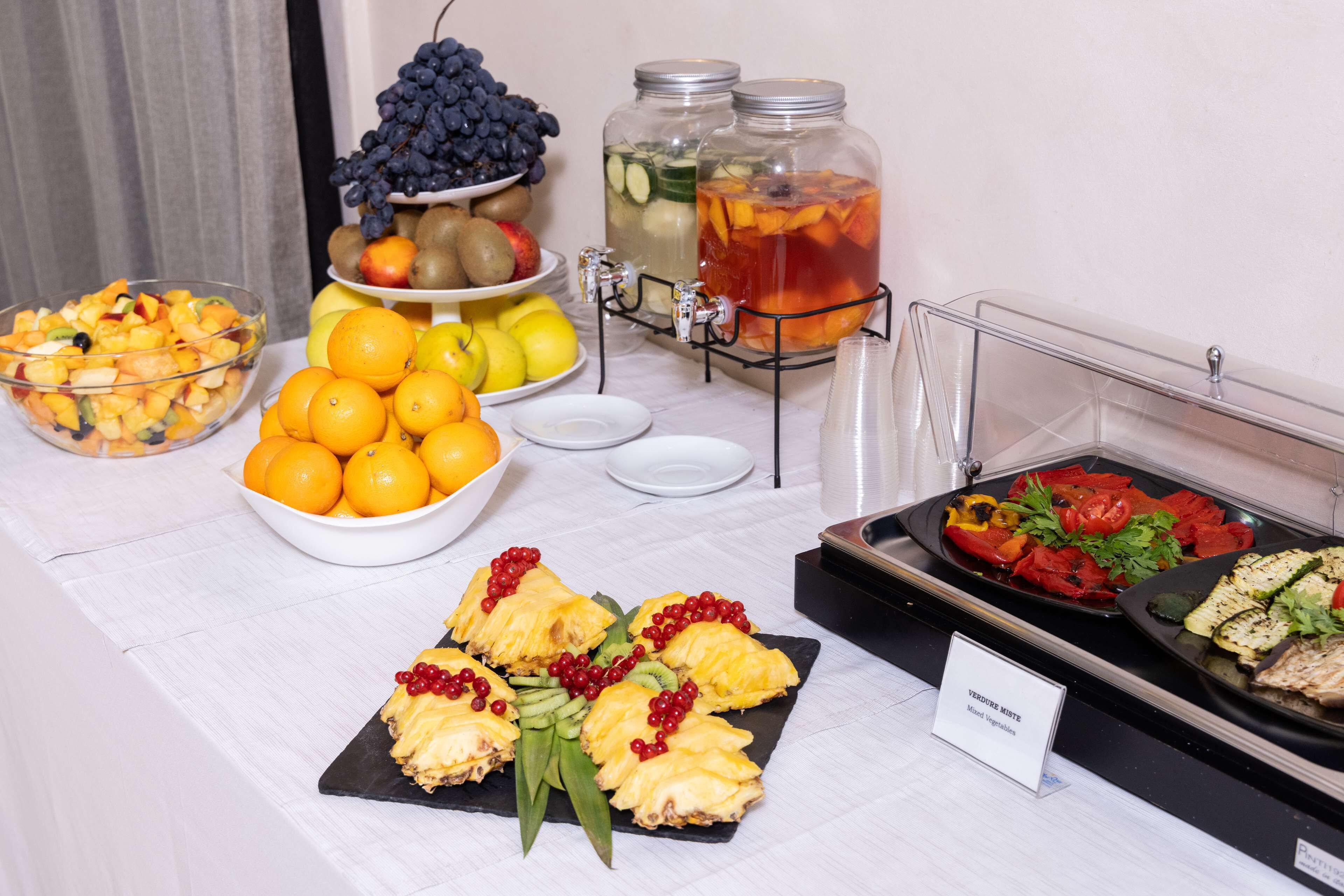 Un buffet proposant une variété de fruits, un saladier rempli de fruits et un panneau indiquant les options végétariennes.
