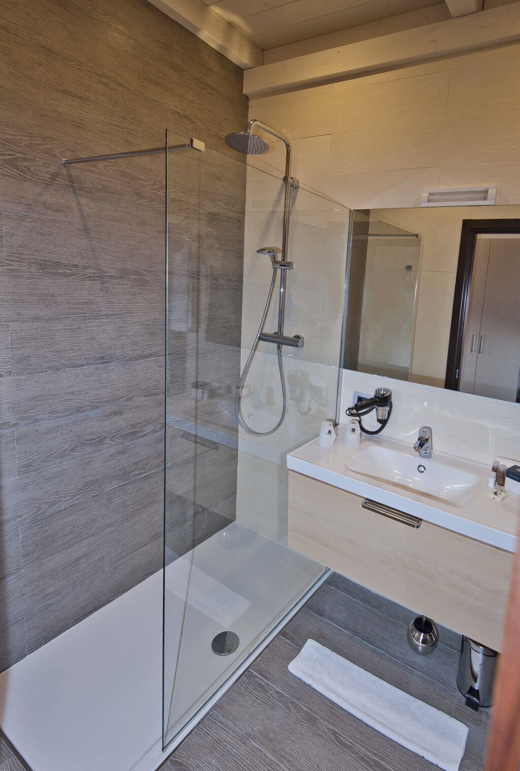 A modern bathroom with a glass shower enclosure, a sink with a mirror, and a towel rack.