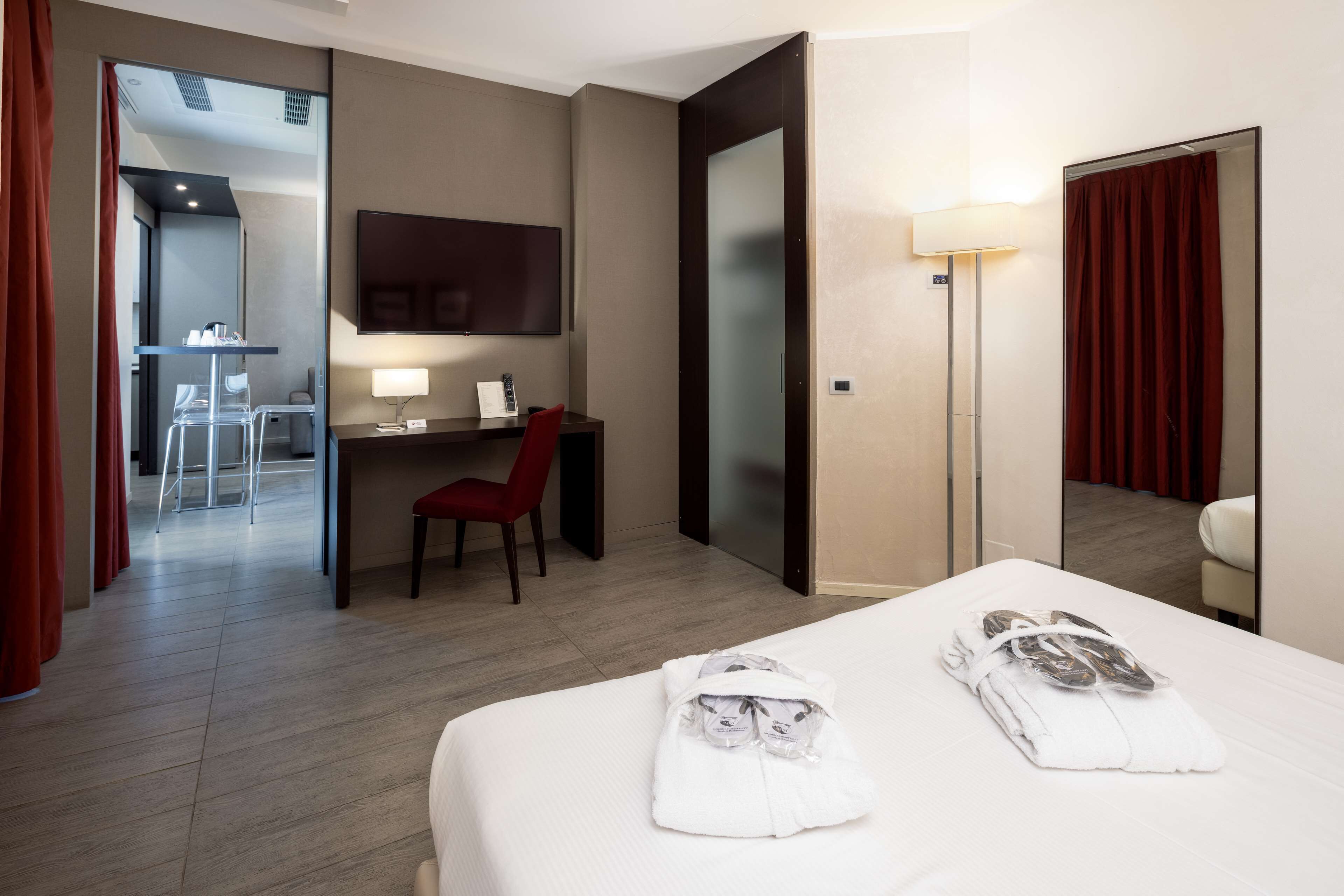Une chambre d’hôtel comprenant un lit, un bureau avec une chaise, une télévision et un miroir.