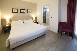 A hotel room with a large bed, two bedside tables with lamps, a red chair, and a shower area. - Best Western Plus Hotel Modena Resort (Formigine)