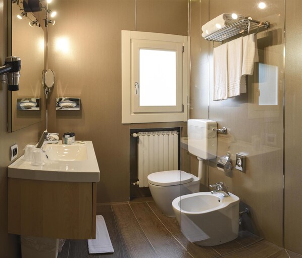 A modern bathroom with a sink, bidet, toilet, and a mirror.