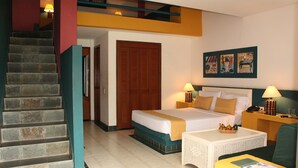 A hotel room with a bed, a desk, a chair, a staircase, and a door. - Hotel Guadaira Resort (Melgar)