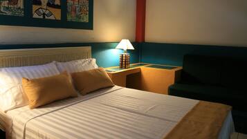 Une chambre d’hôtel avec un lit, une table de chevet avec une lampe, un canapé vert et des œuvres d’art accrochées au mur.