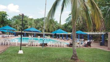 Relax by the resort pool surrounded by palm trees and tropical vegetation.
