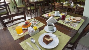Een ontbijttafel gedekt met brood, fruit en een kop koffie.