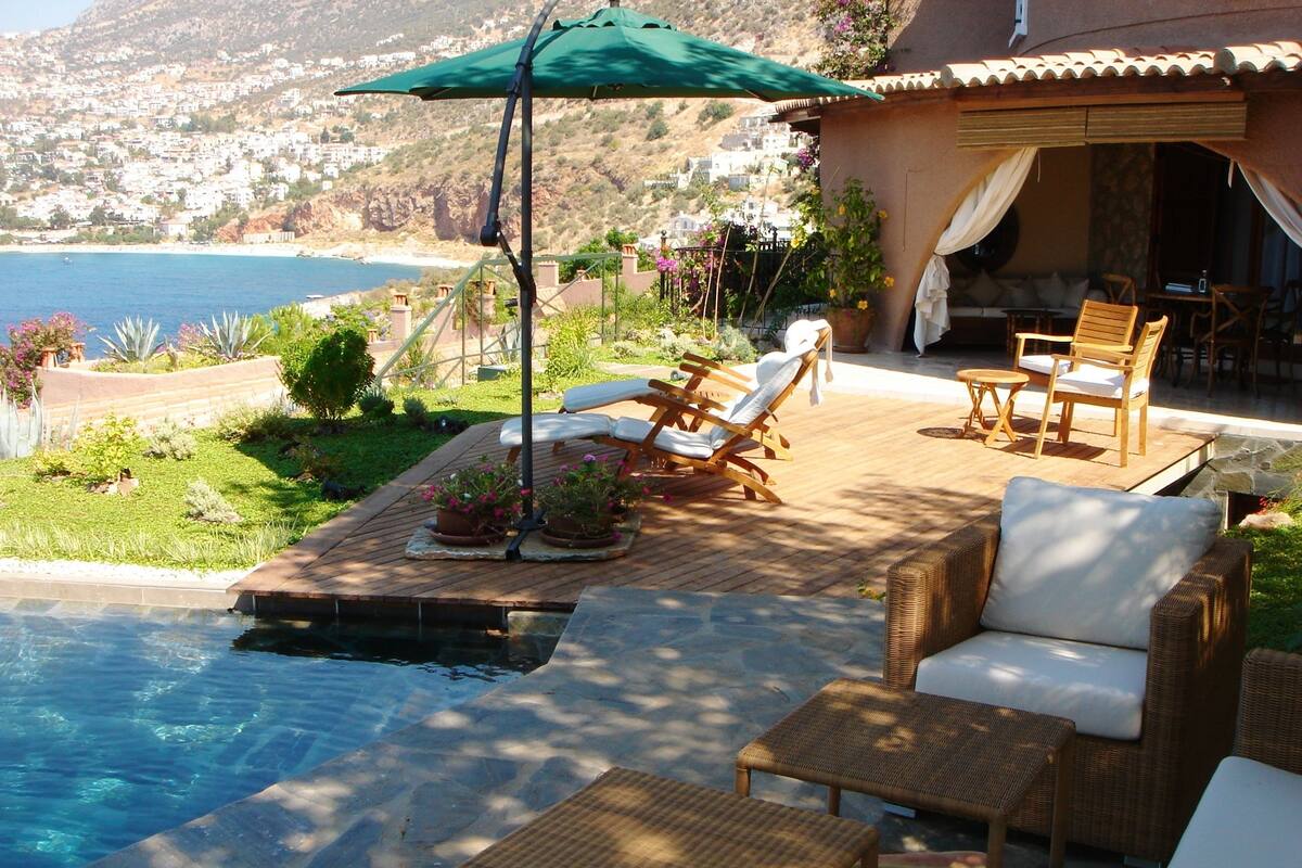 A poolside area with lounge chairs, a table, and an umbrella.