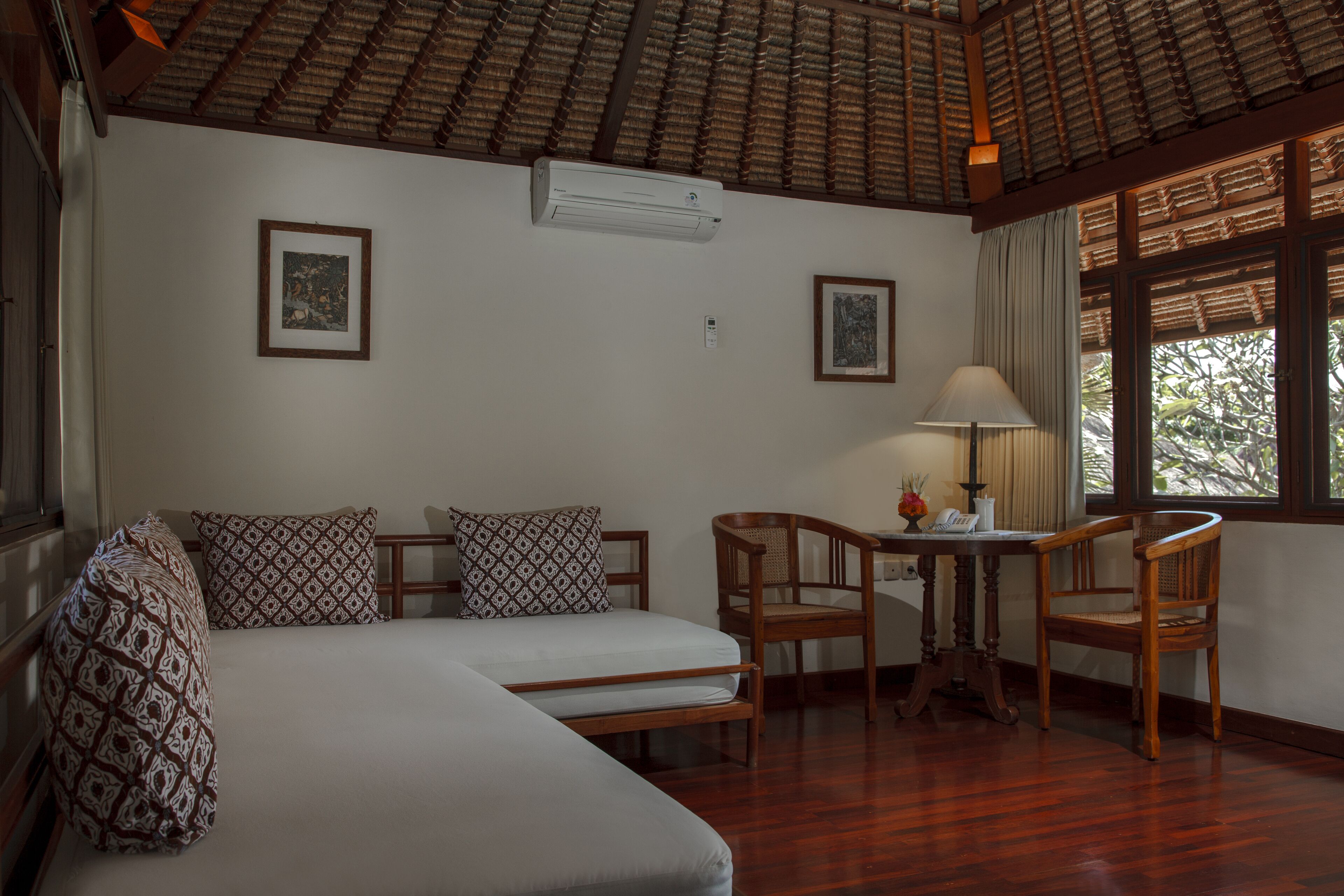 A room with a bed, two chairs, a table, and a window with a view of trees.