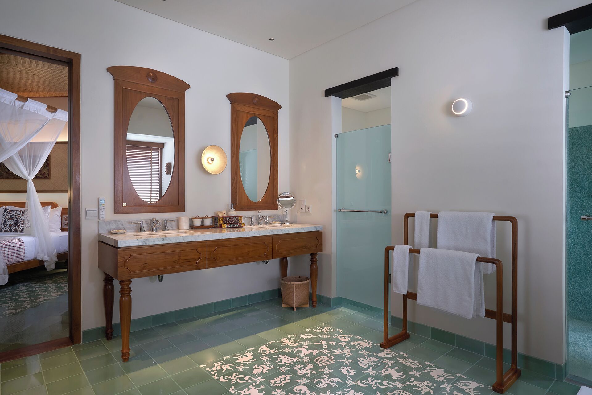 A bathroom with a wooden vanity, two mirrors, a glass shower enclosure, and a towel rack.