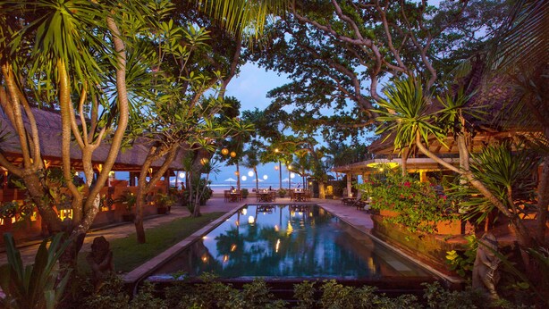 An outdoor pool area with a seating arrangement and a view of the ocean.
