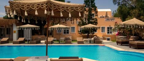 A pool area with lounge chairs and umbrellas.
