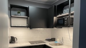 Una cucina compatta con mobili neri, un forno a microonde, un lavandino e una lavastoviglie.