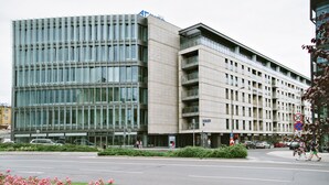 Un edificio moderno con facciata in vetro e un parcheggio antistante.
