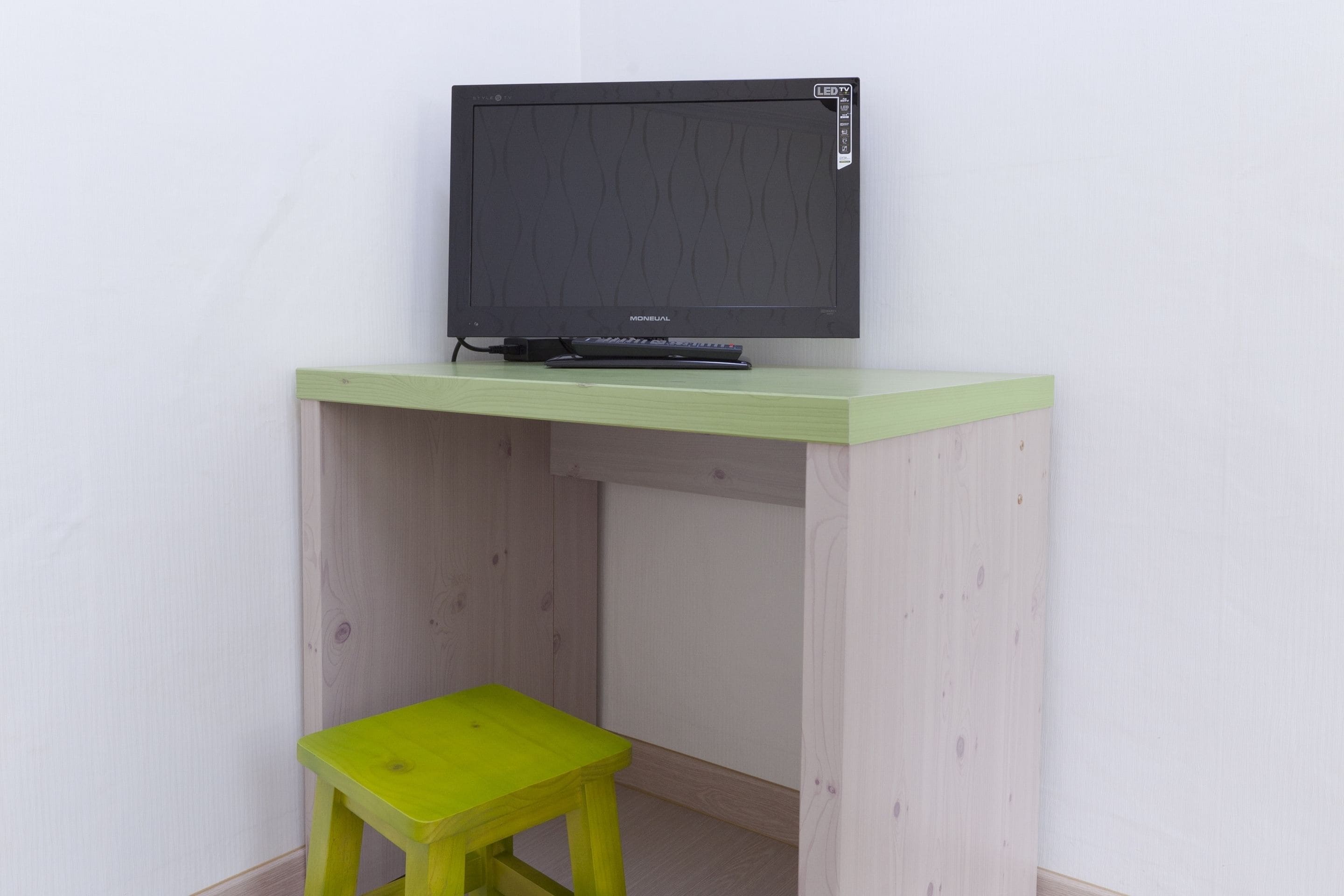A small wooden desk with a television and a stool.