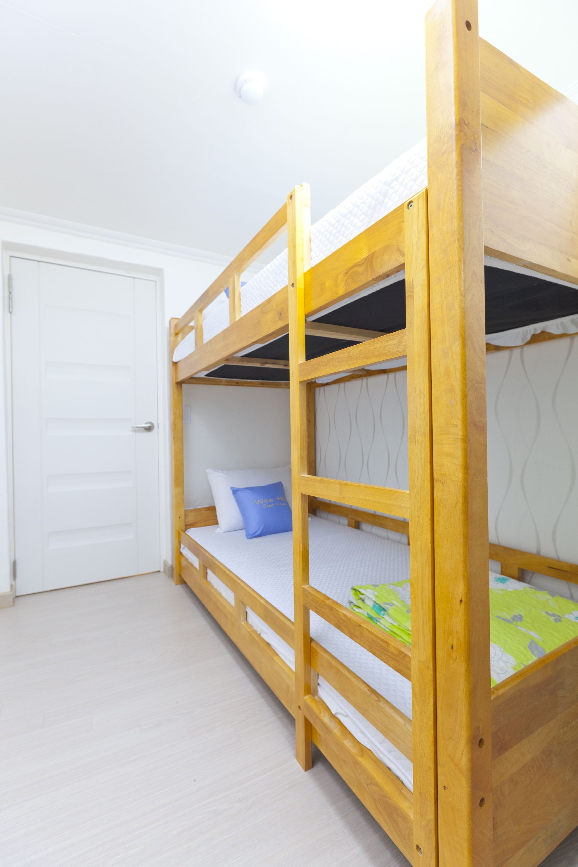 A bunk bed with two levels, a white door, and a light-colored floor.