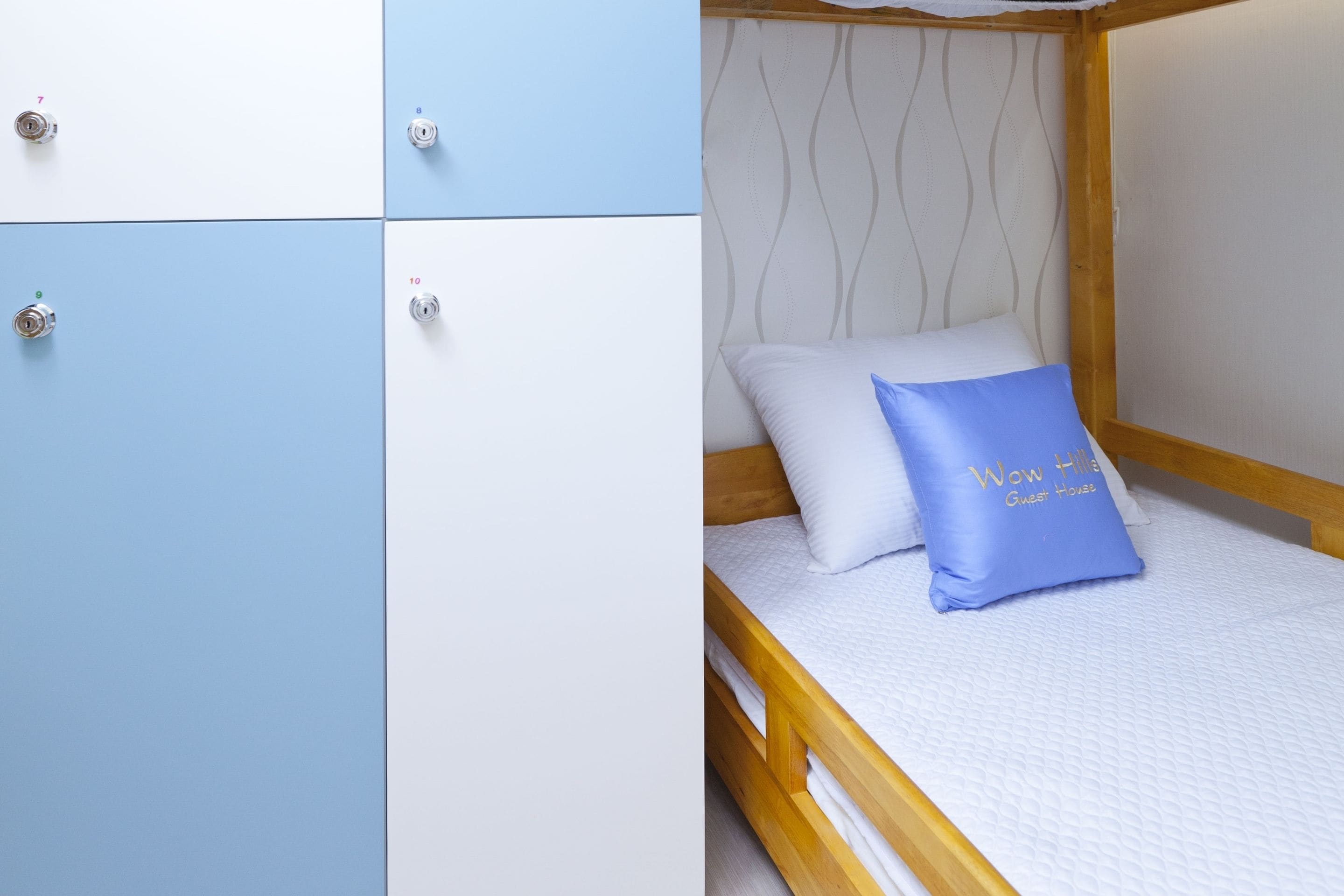 A bedroom with a bed, a blue pillow, and a wooden headboard.