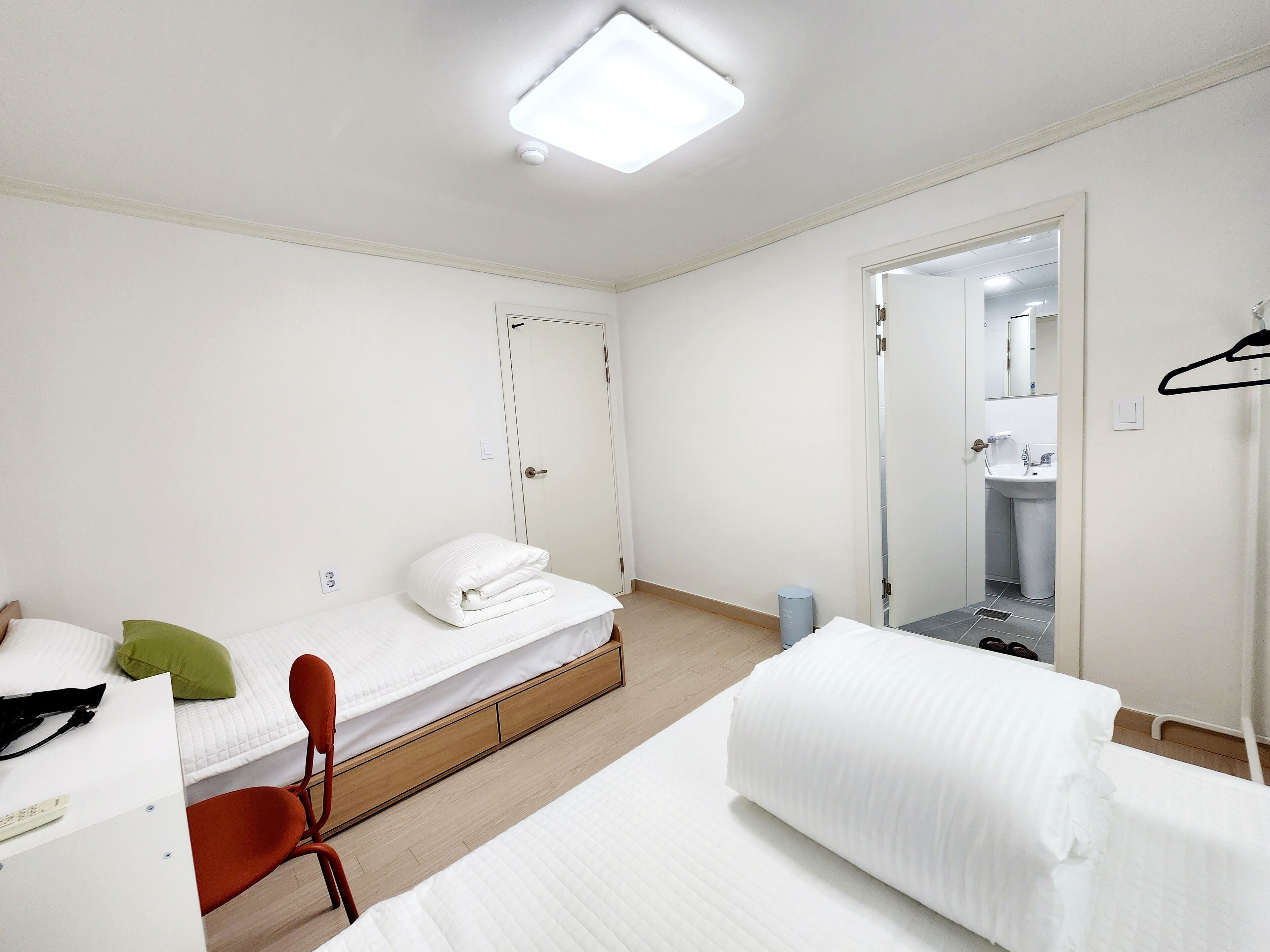 A hotel room with a bed, a desk, a chair, and a bathroom visible through an open door.