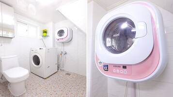 A bathroom with a washing machine, toilet, and a wall-mounted dryer.