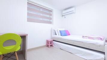 A bedroom with a bed, a desk, a chair, and a window with blinds.
