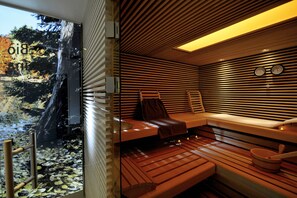 A sauna with wooden benches, a view of a waterfall, and a clock on the wall. - Landidyll Hotel-Restaurant Birkenhof (Klosterkumbd)