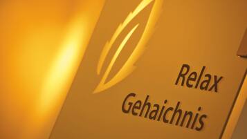 Ein Schild mit dem Schriftzug 'Relax Gehaichnis' und einem stilisierten Blatt-Design.