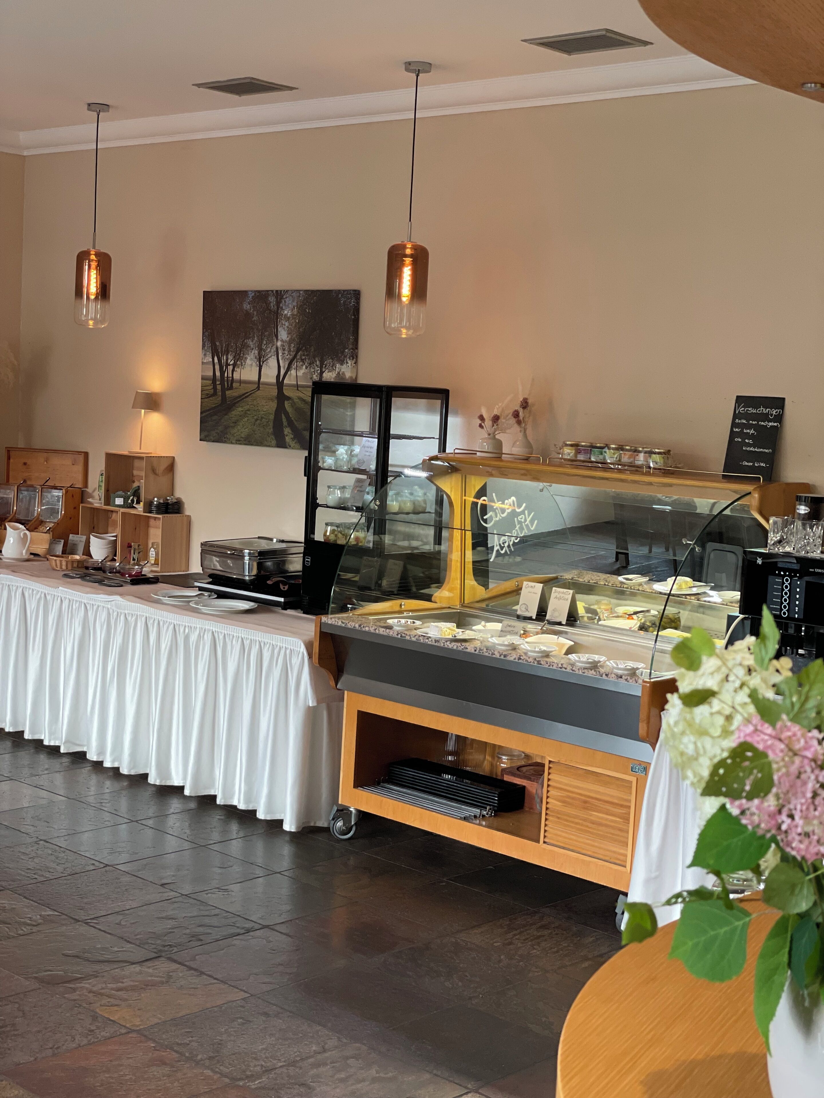 Un buffet composé d'une vitrine réfrigérée, d'un comptoir en bois et d'un éclairage suspendu.
