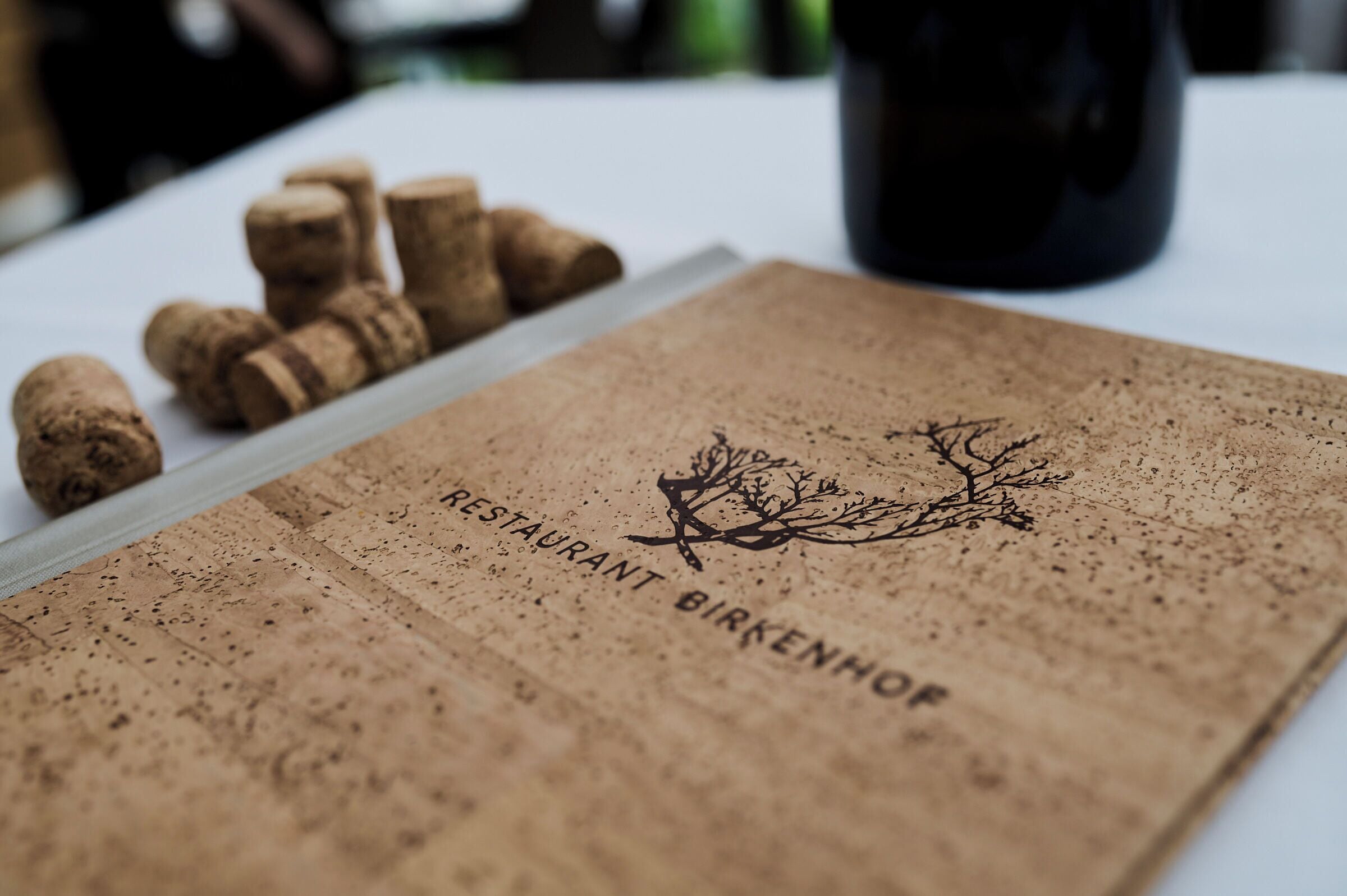 Um apoio de cortiça com o texto "RESTAURANT BRÄKENHOF" e um desenho de galho de árvore.