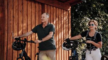 Twee mensen op elektrische fietsen voor een houten gebouw.