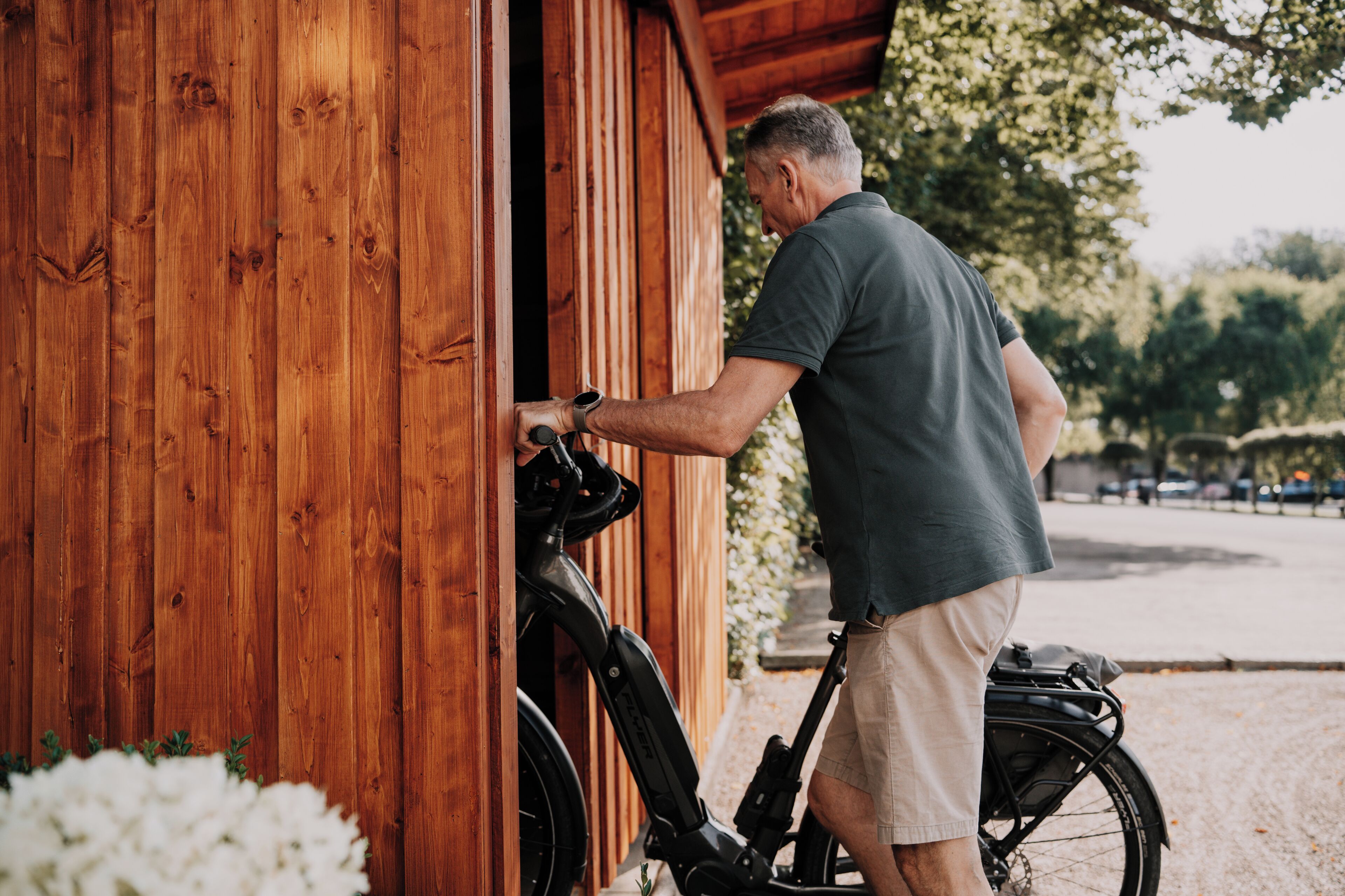 A man opening a wooden door, with a bicycle parked outside.