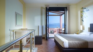 A hotel room with a bed, a desk, a chair, a view of the sea, and a balcony. - Aeolis Apartments & Studios (Lesvos)