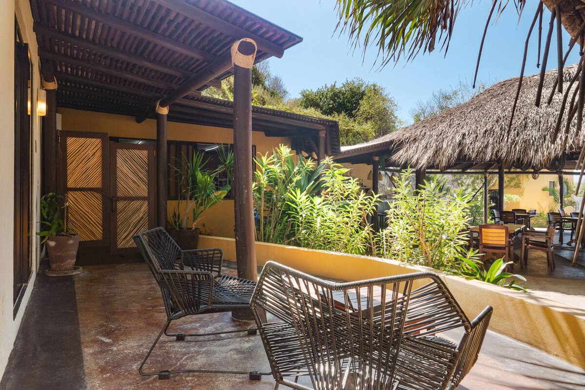 An outdoor seating area with wicker chairs and a thatched roof structure.