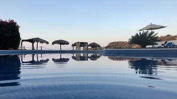 Una piscina al aire libre, sillones reclinables de piscina