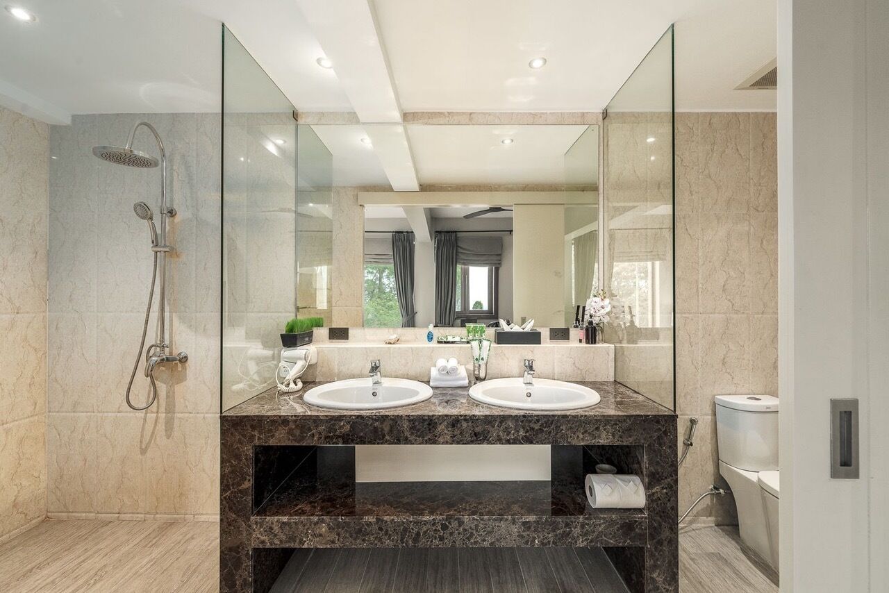 Une salle de bain moderne avec deux lavabos, une douche et un grand miroir.