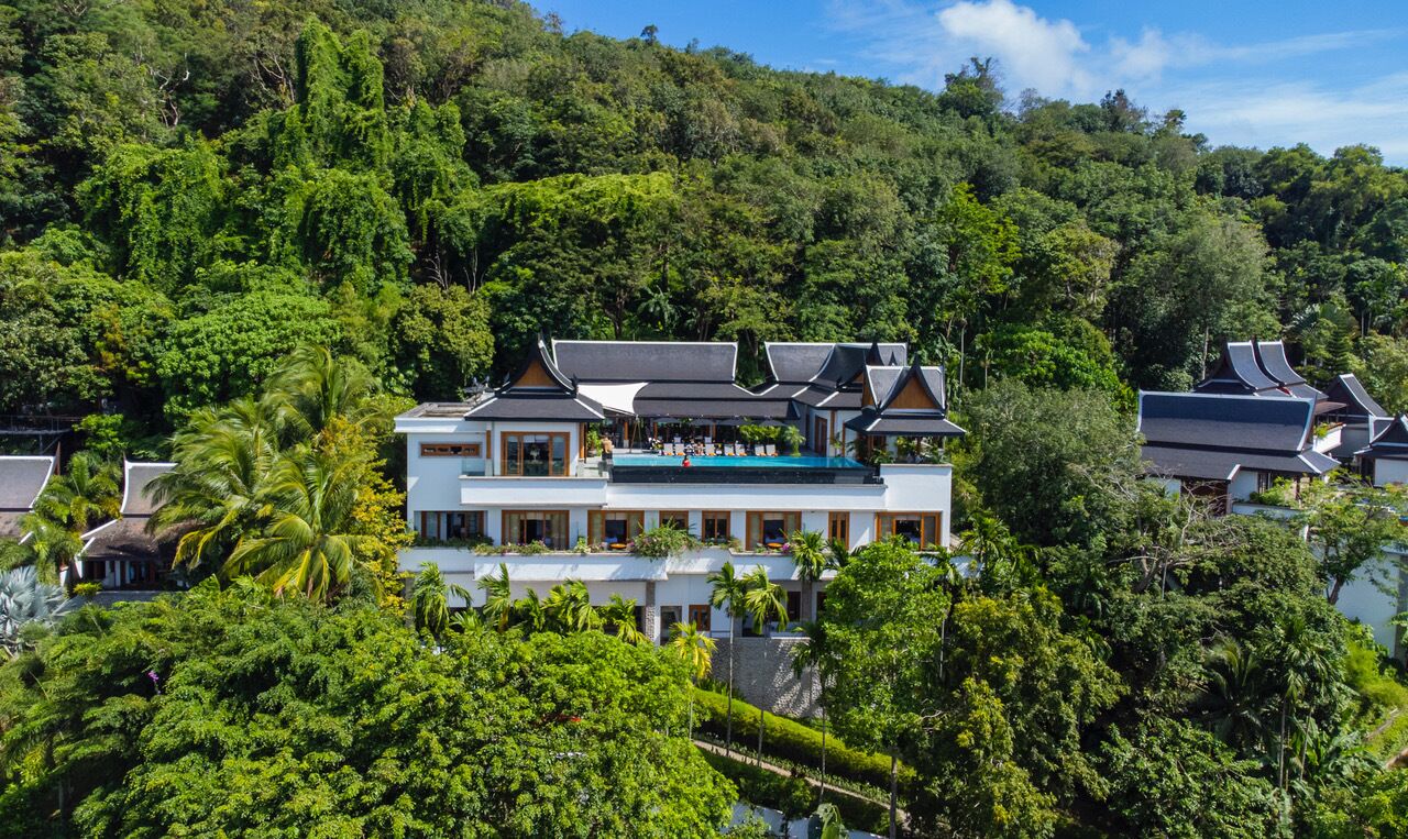 A resort with multiple buildings, lush greenery, and a pool area.