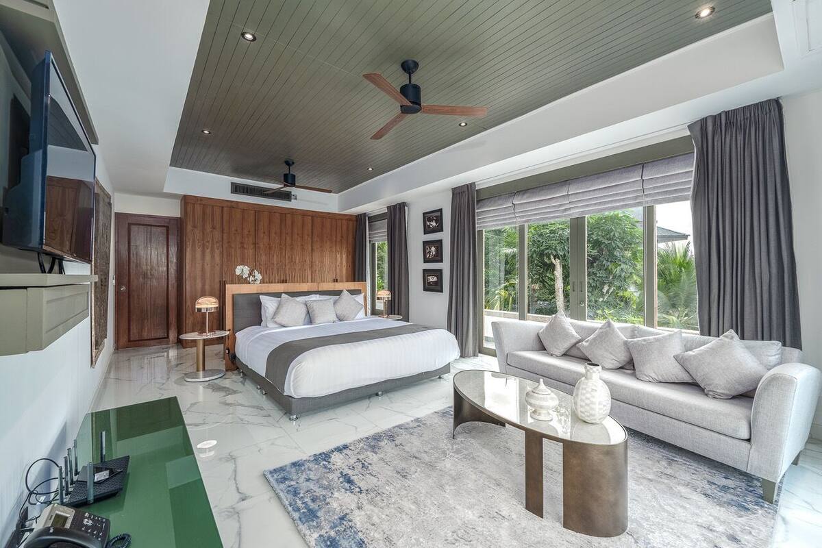 Una habitación de hotel moderna con una cama grande, un sofá, una mesa de centro y un televisor.