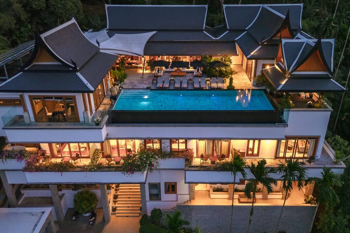Una casa moderna de varios pisos con piscina, mobiliario exterior y jardines exuberantes.