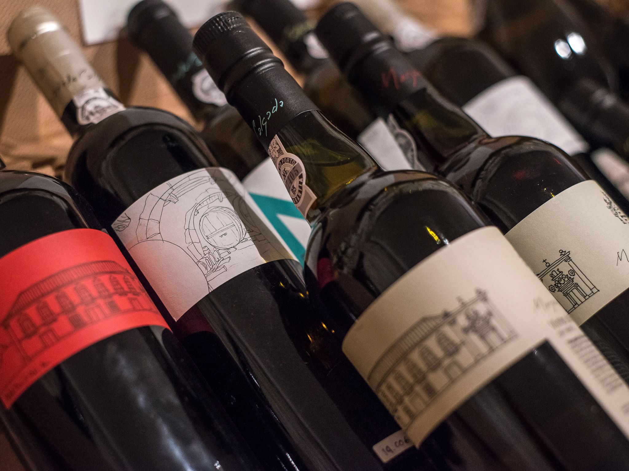 Varias botellas de vino con etiquetas, algunas con dibujos arquitectónicos.