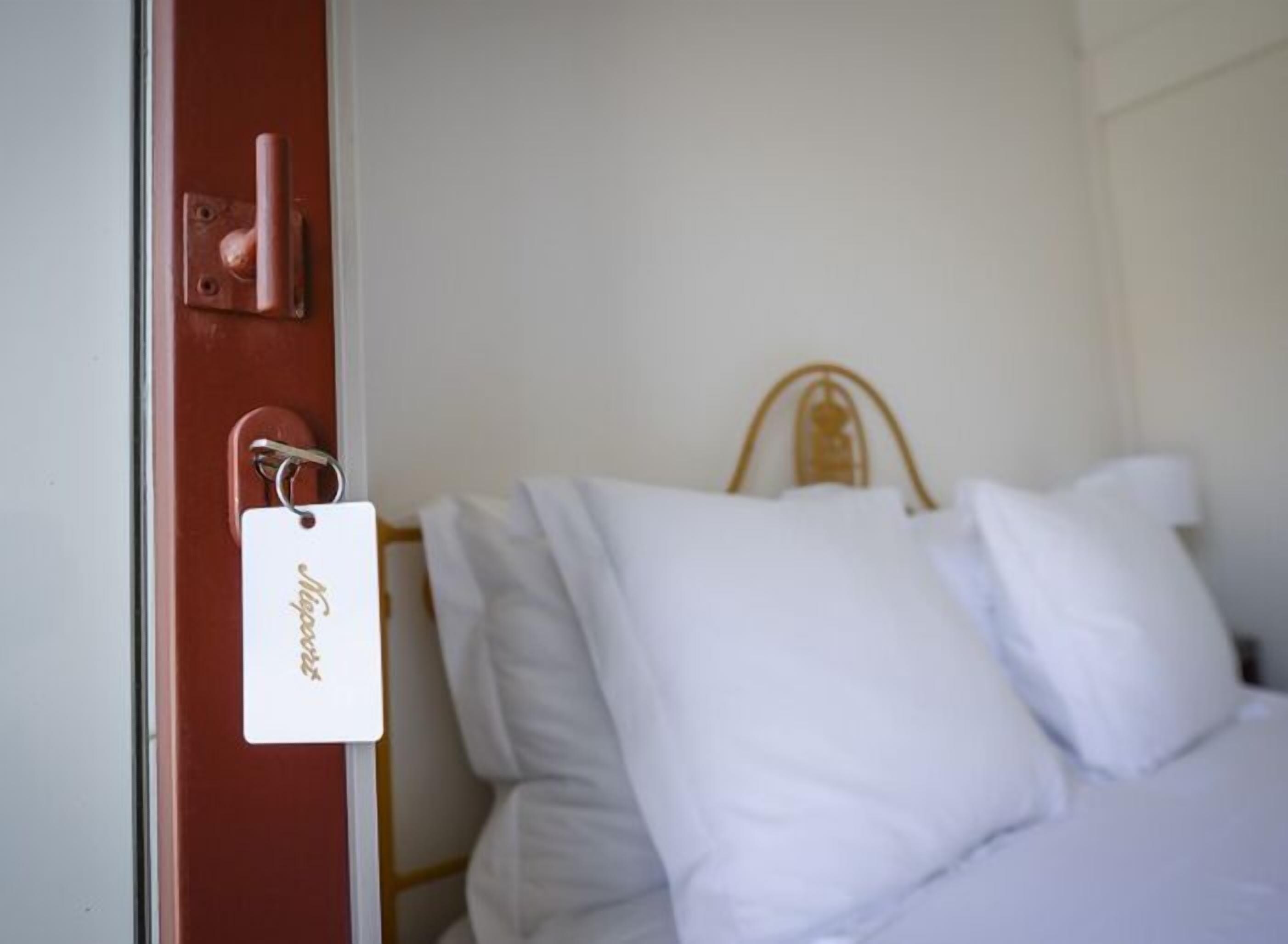 A hotel room with a bed, a door with a keycard, and a white wall.